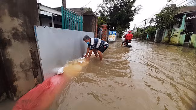 Người dân huyện Tuy Phước (Bình Định) dùng bao cát chặn nước tràn vào nhà. Ảnh: Xuân Thức Người dân huyện Tuy Phước (Bình Định) dùng bao cát chặn nước tràn vào nhà. Ảnh: Xuân Thức
