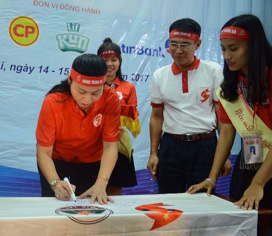  Phó Chủ tịch UBND tỉnh Huỳnh Nữ Thu Hà (bên trái) bút ký lên Lá cờ lưu niệm của Hành trình Đỏ 2017. Ảnh: P.L