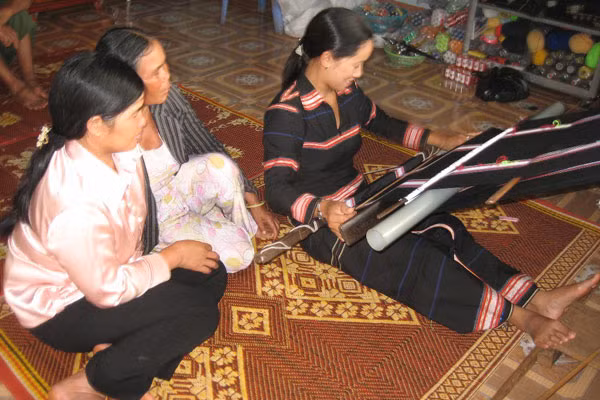 Rơ Lan Pel chỉ cách dệt thổ cẩm cho chị em trong làng. Ảnh: Lê Hòa