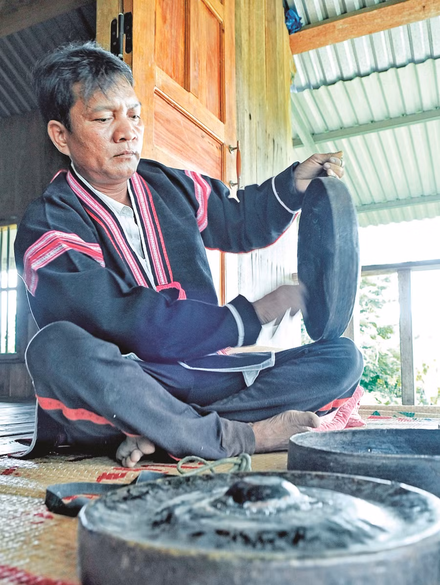 Nghệ nhân Ksor Kok “chữa bệnh” cho chiêng. Ảnh: Hoàng Ngọc 