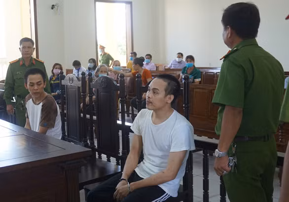 Đặng Ngọc Minh (áo thun trắng) và Đặng Ngọc Giàu được lực lượng công an giám sát chặt tại tòa - Ảnh: LAN NGỌC