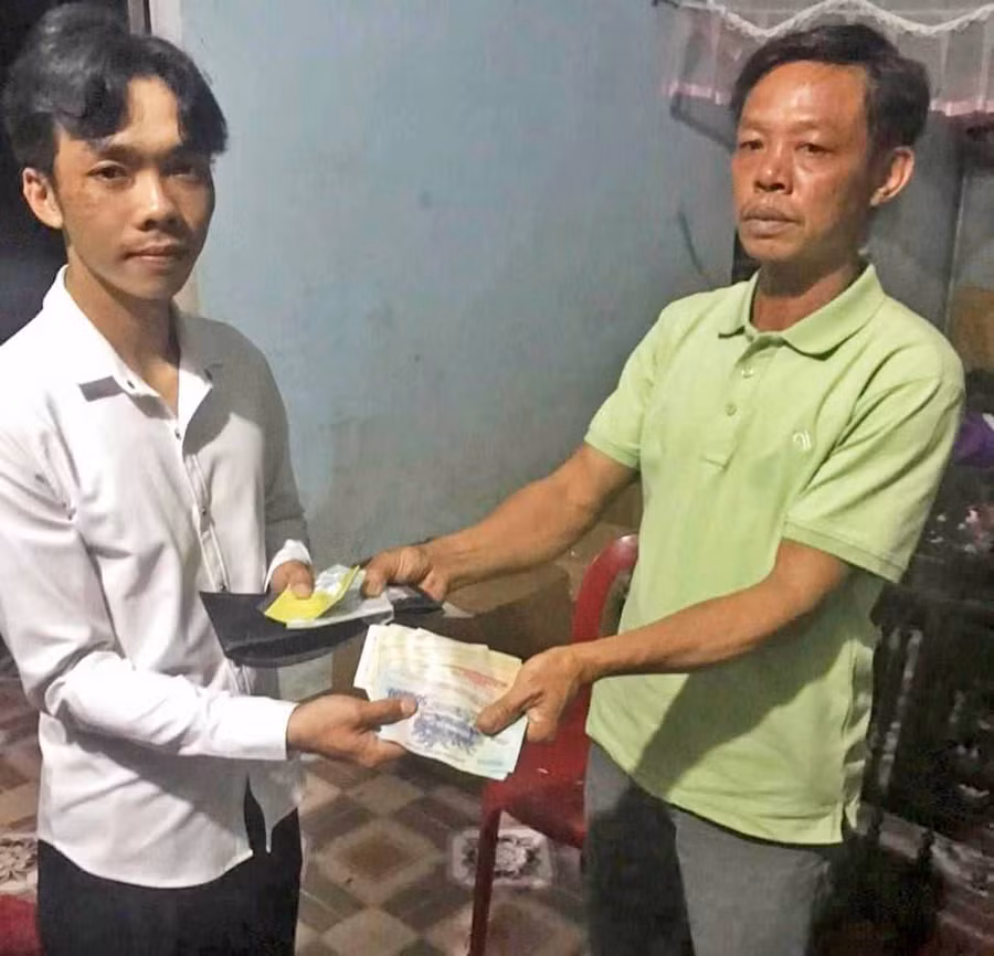 Anh Lê Văn Oai (bìa phải) trao trả toàn bộ giấy tờ và số tiền 27.766.000 đồng cho anh Nguyễn Minh Hoàng. Ảnh: Thúy Trinh