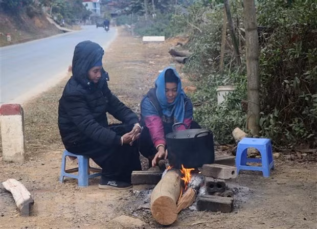 Người dân sinh sống dưới chân đèo Pha Đin, cạnh Quốc lộ 6 đốt lửa sưởi ấm, chống chọi với giá lạnh. (Ảnh: Xuân Tiến/TTXVN)