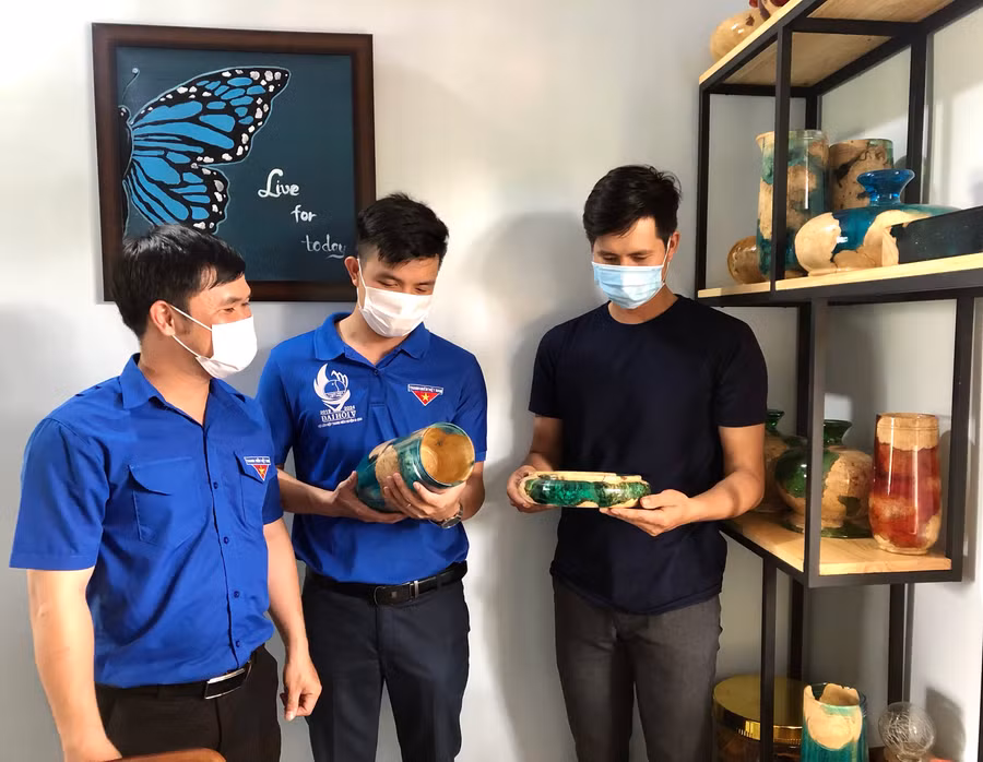 Anh Nguyễn Quyết Thắng (bìa phải) giới thiệu sản phẩm được làm từ gốc cà phê với đoàn viên, thanh niên. Ảnh: Thủy Bình