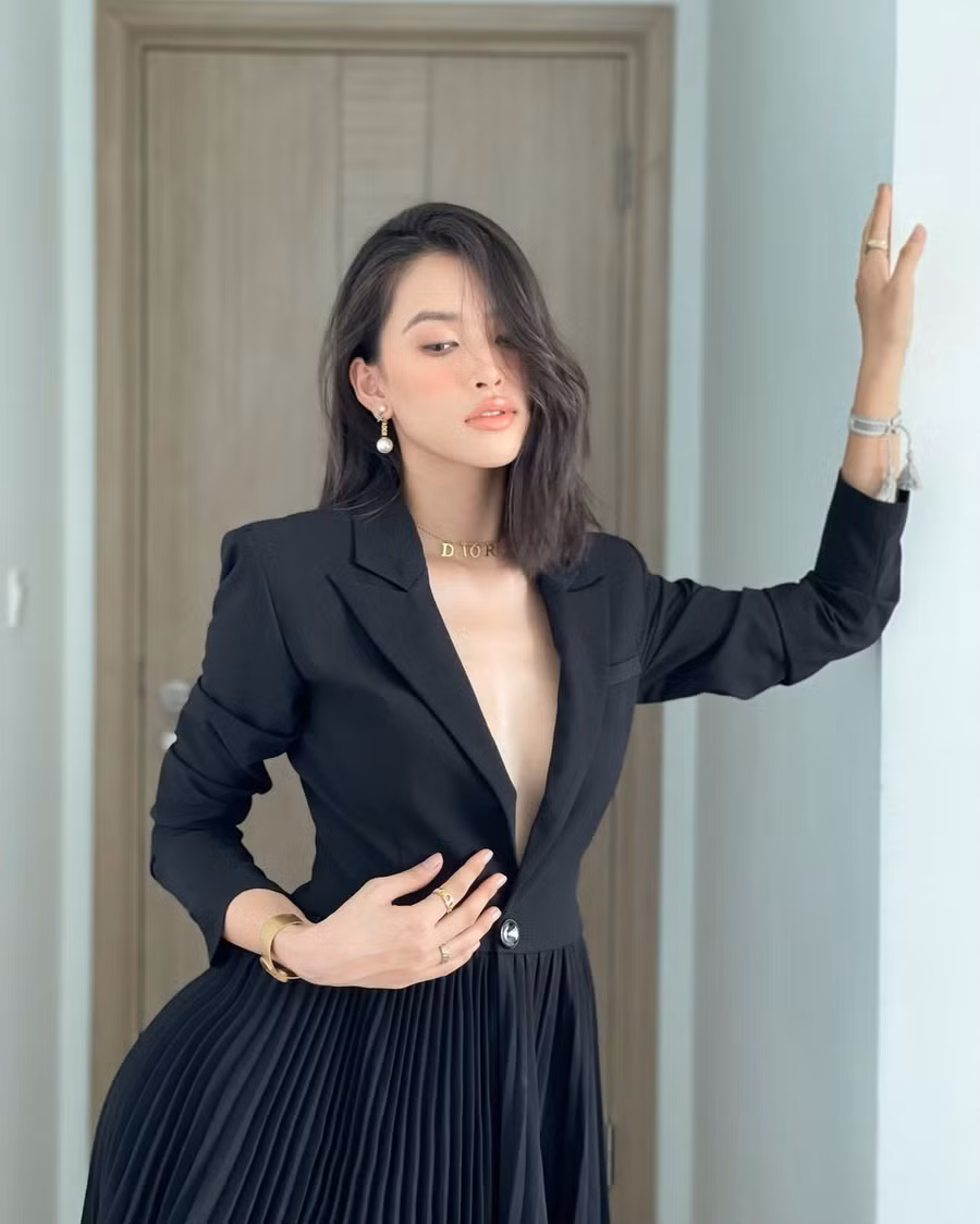 Hoa hậu Việt Nam 2018 Trần Tiểu Vy khoe nhan sắc “cực phẩm” và vóc dáng hoàn hảo trong thiết kế đầm đen xếp ly với phần thân trên dáng vest thanh lịch và thời thượng. Người đẹp tạo điểm nhấn và hoàn thiện set đồ bằng phụ kiện trang sức dây chuyền Dior, bông tai, vòng tay kiểu dáng thanh mảnh và tinh tế. 