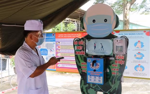  Thiếu tá Lê Mạnh Hùng với sản phẩm robot rửa tay, sát khuẩn. (Ảnh: Hồng Điệp/TTXVN)
