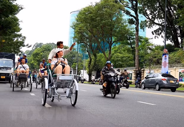 Du khách quốc tế tham quan trung tâm Thành phố Hồ Chí Minh bằng xích lô. Ảnh: Hồng Đạt/TTXVN