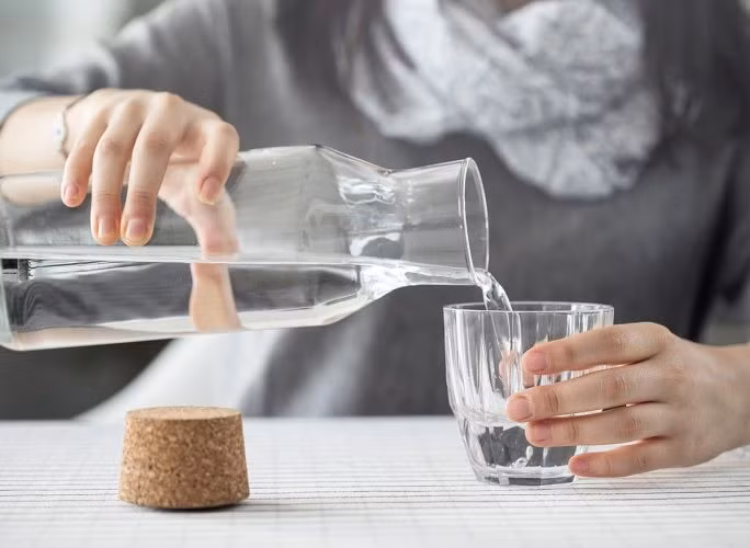 Cách uống nước đúng là thư giãn và ngồi thẳng lưng rồi uống. Ảnh: Shutterstock