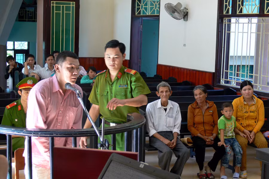 Bị cáo Trần Quang Hiếu trước vành móng ngựa. Ngồi ở hàng ghế phía sau là cha mẹ ruột, vợ và con trai tên Thái của Hiếu. Ảnh: Nguyễn Xuân