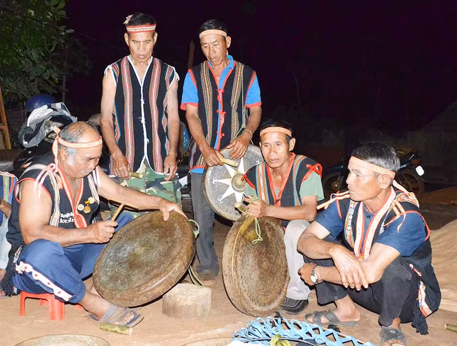 Già Đâu (bìa phải) lấy lại âm chuẩn cho bộ chiêng của làng để tham gia biểu diễn tại Festival. Ảnh: P.L