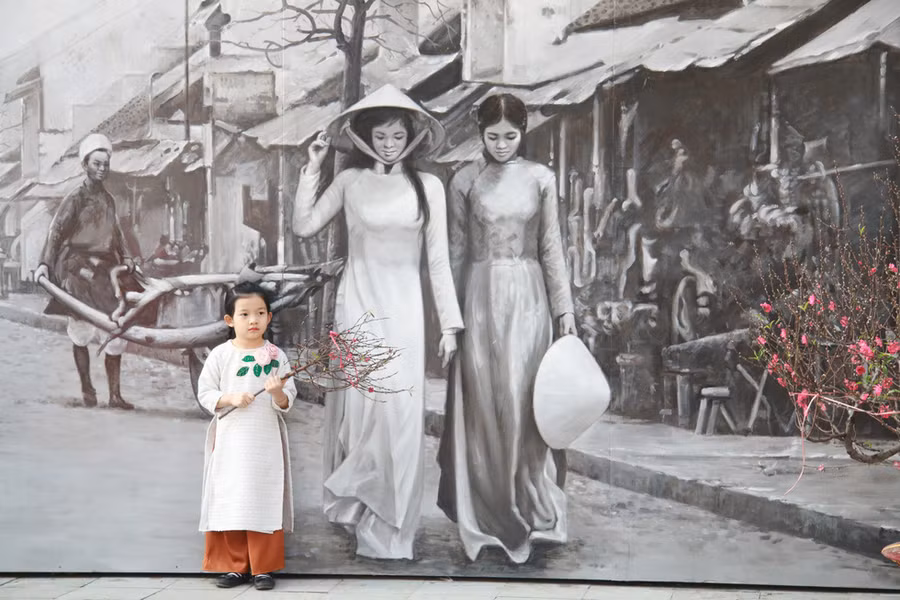 Một cô bé chụp ảnh với bức tranh Phố cổ Hà Nội xưa