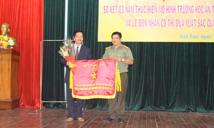  Ông Rơ Lan Lâm-Phó Giám đốc Công an tỉnh trao cờ thi đua xuất sắc của Bộ Công an cho Trường Cao đẳng Sư phạm Gia Lai. Ảnh: N.G