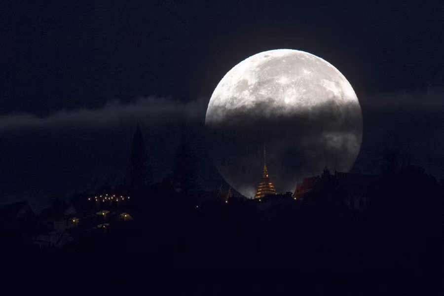 Siêu trăng lấp ló trong mây trên bầu trời Chiang Mai, miền bắc Thái Lan, phía trước là ngôi chùa Wat Phrathat Doi Suthep. "Siêu trăng" là thuật ngữ xuất hiện gần đây để chỉ thời điểm trăng tròn và ở cận điểm - điểm gần nhất của nó so với Trái Đất trong quỹ đạo hình elip. 7