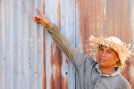 Trưởng thôn chỉ vết thủng trên tường có thể là nguyên nhân làm cháu H’Nguyệt bị trọng thương. Ảnh: N.G