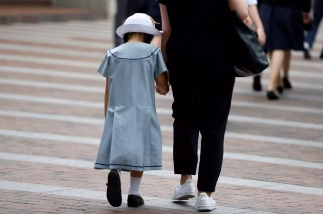 Một học sinh đi bộ cùng mẹ đến trường ở thủ đô Tokyo, Nhật Bản - Ảnh: Reuters