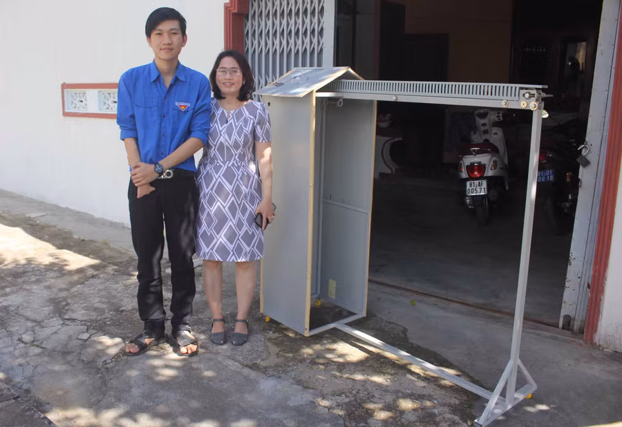  Em Trần Kế Tuấn Vương và cô giáo Tạ Thị Hạnh bên chiếc máy phơi đồ. Ảnh: H.S