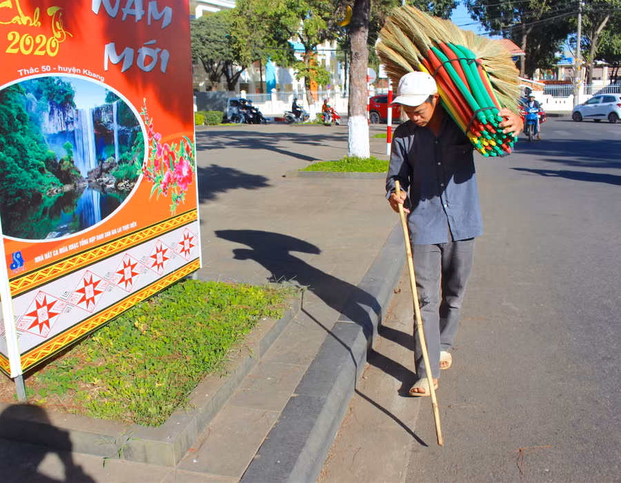 Chàng trai khiếm thị Nông Văn Cường tranh thủ đi bán chổi trong những ngày cuối năm. Ảnh: Mộc Trà