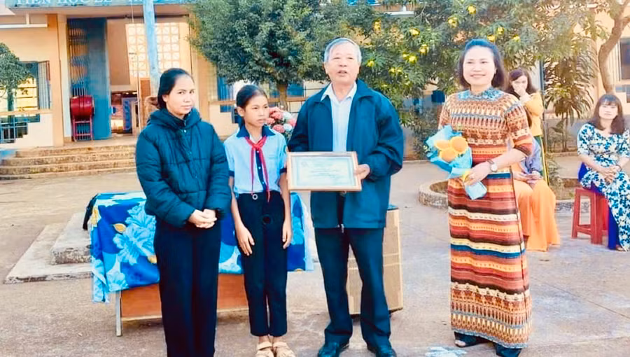 Ông Đinh Xuân Thao-Chủ tịch Hội khuyến học huyện Ia Grai tặng giấy chứng nhận danh hiệu "Học không bao giờ cùng" và số tiền 3 triệu đồng cho em Puih H' Pưn-Trường Tiểu học Lý Tự Trọng, xã Ia Chía, huyện Ia Grai. Ảnh: Xuân Thao